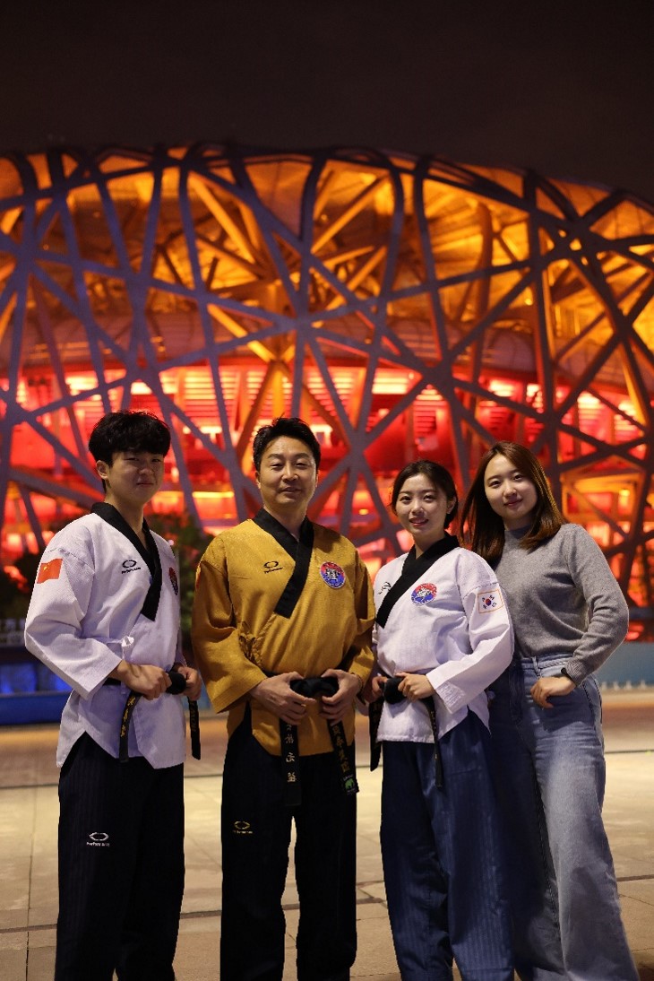 Master Seo and his three children are making a pose in front of the main stadium of the Beijing Olympics.