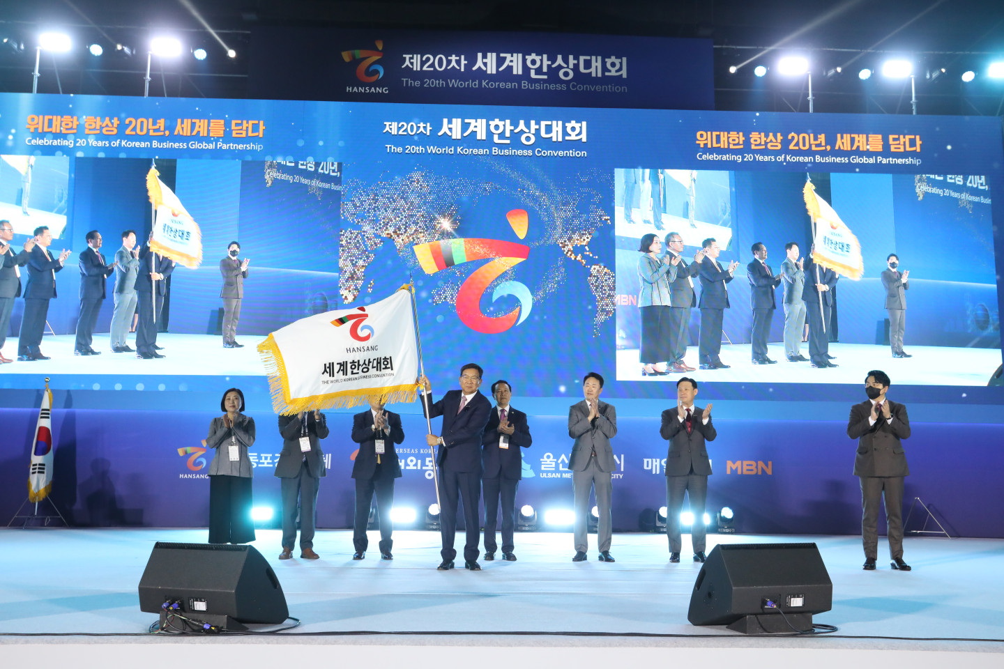 Convention Chief Kim Jeom-bae announcing the opening of the 20th Korean World Business Convention while waving the convention flag