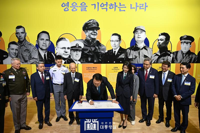 President Yoon Suk Yeol (middle) on June 25 signs the visitor log of an exhibition commemorating the 70th anniversary of the bilateral alliance with the U.S. at the National Museum of Korean Contemporary History in Seoul's Jongno-gu District